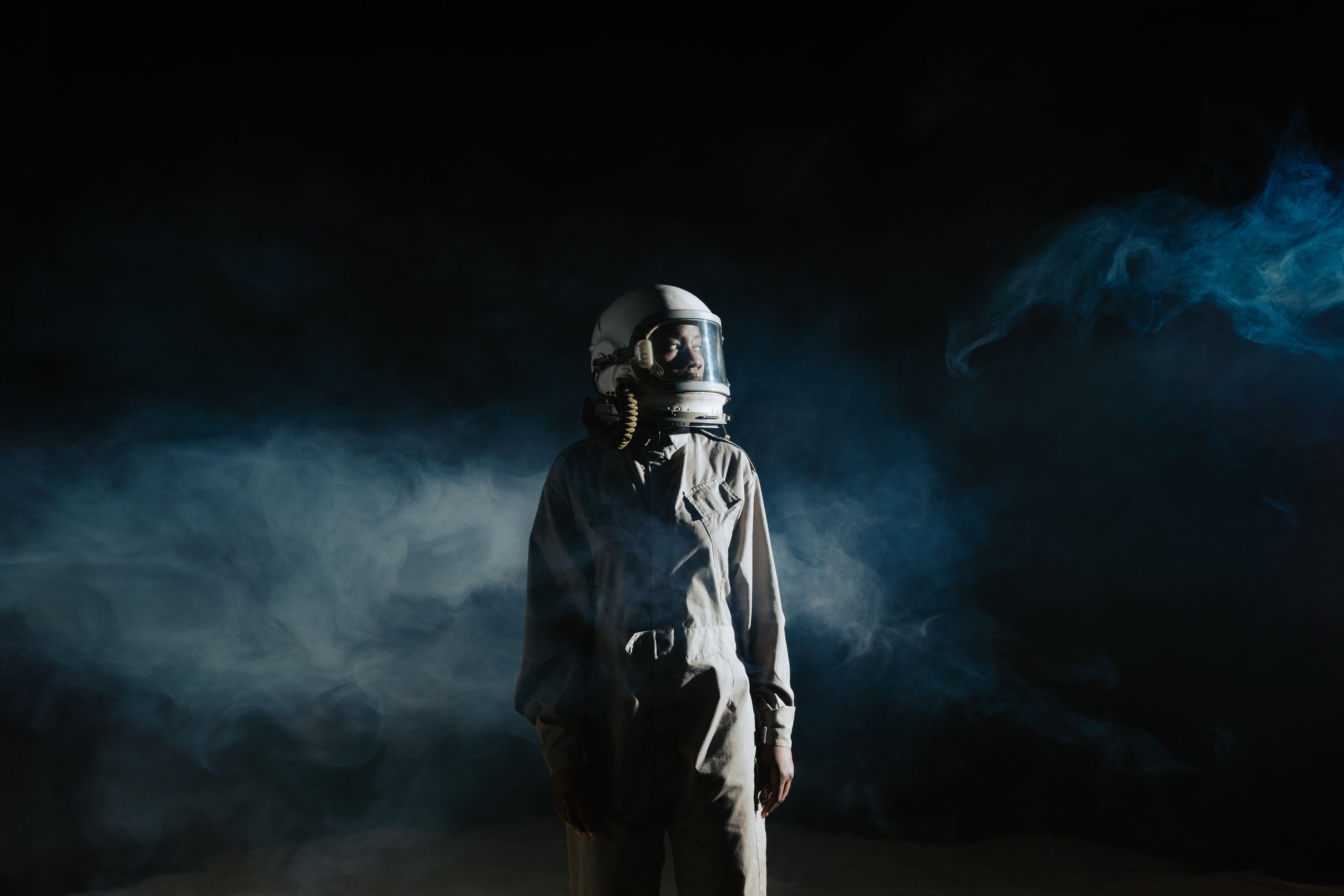 A person in a space suit against a dark, smoke-filled background